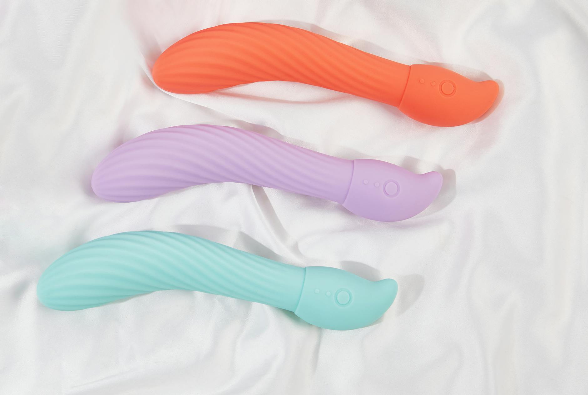 Tres vibradores clitorales Lemon en colores brillantes sobre tela blanca, mostrando su textura suave y diseño ergonómico