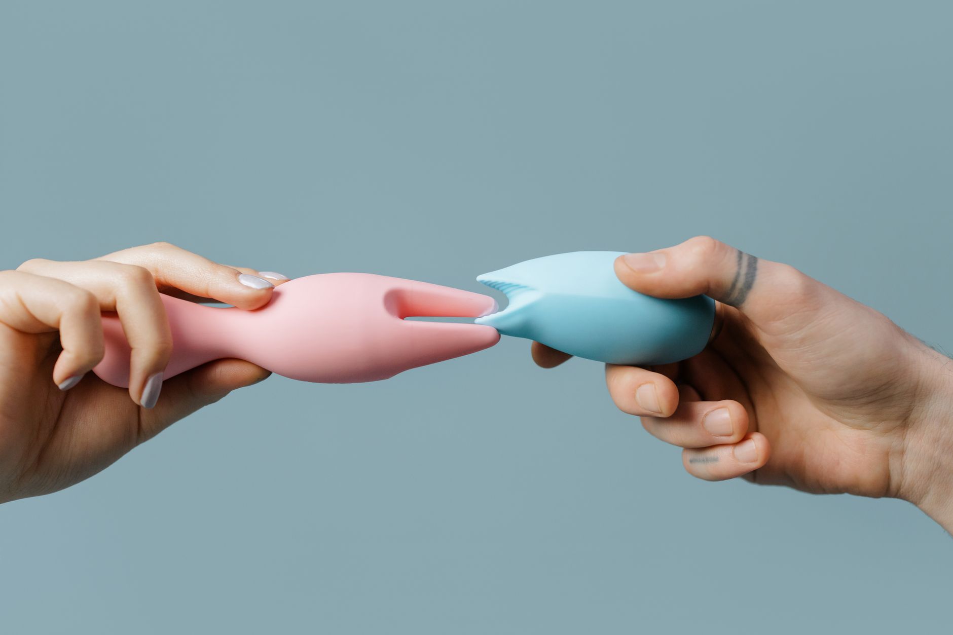Hand holding a blue silicone vibrator against a purple background, representing self-care and clitoral pleasure at any age