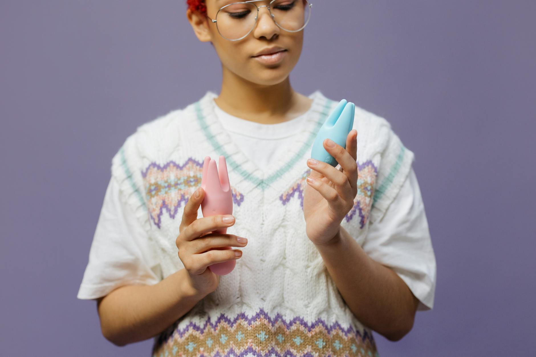 Woman holding a blue silicone clitoral vibrator with thoughtful expression