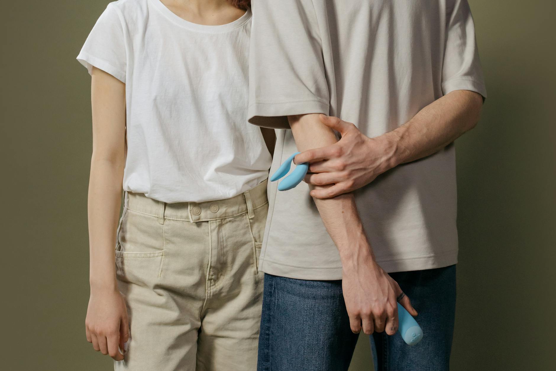 A couple holding a blue vibrator together, symbolizing reconnection and shared intimacy