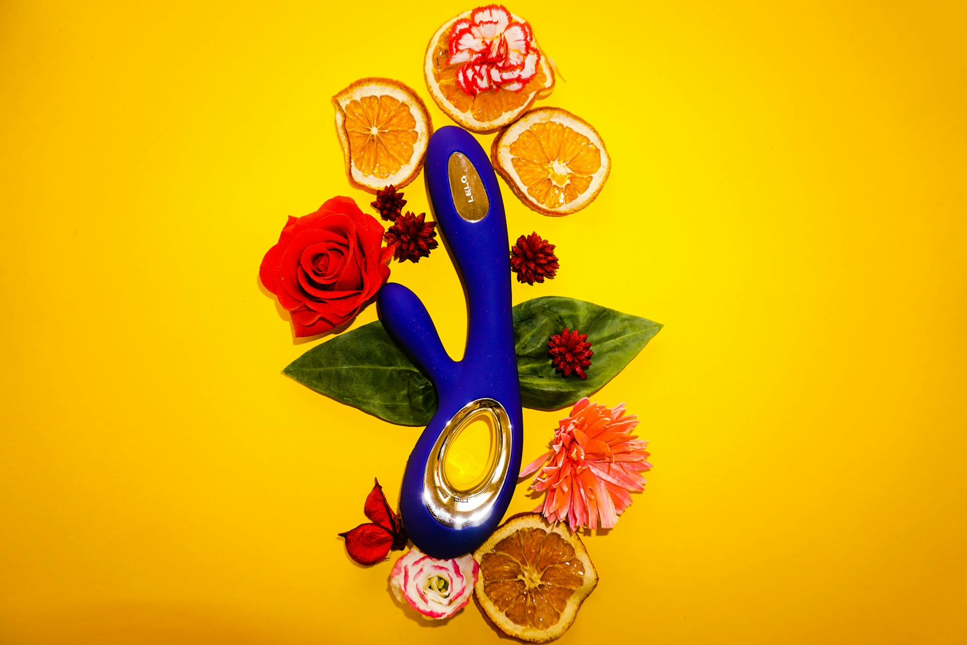 Lemon vibrator surrounded by fresh citrus and flowers on a bright yellow background