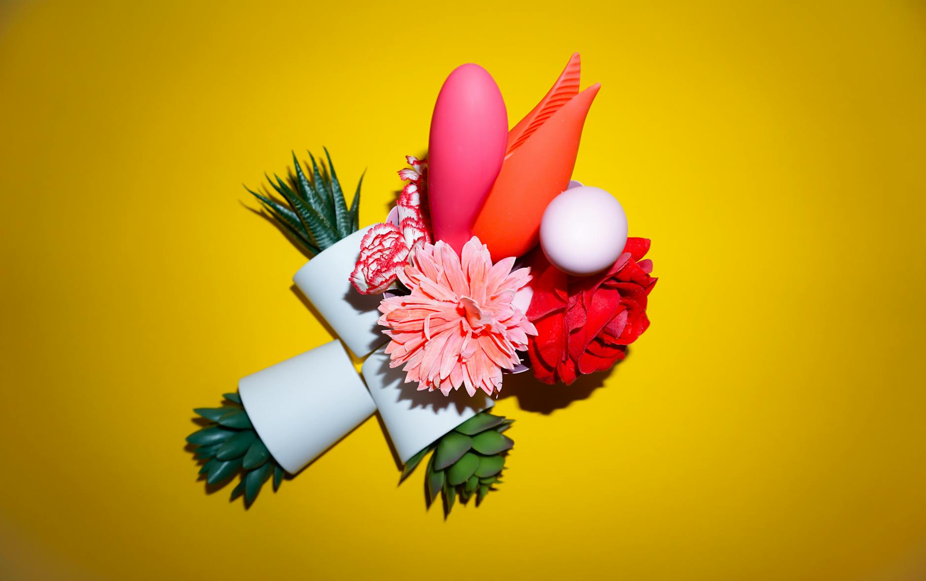 Colorful arrangement of vibrators and pleasure items on a bright yellow surface
