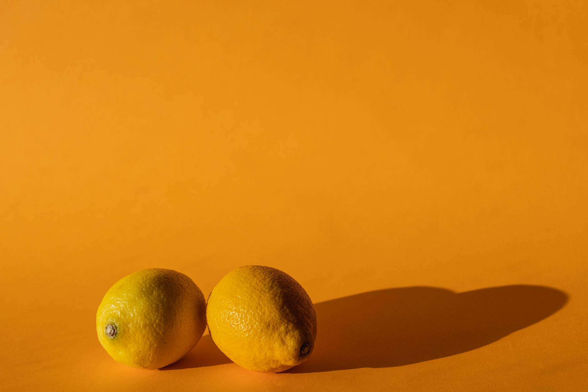 A blue vibrator surrounded by flowers and citrus slices on a bright yellow background